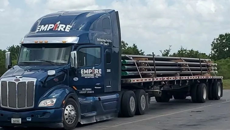 An Empire Express Peterbilt flatbed loaded with steel pipe, secured and ready to roll